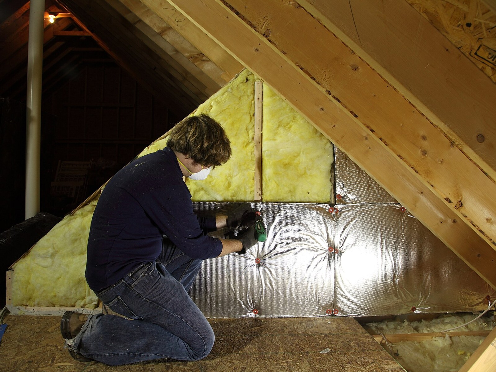 Two Guys Energy Solutions technician at work in a residential attic